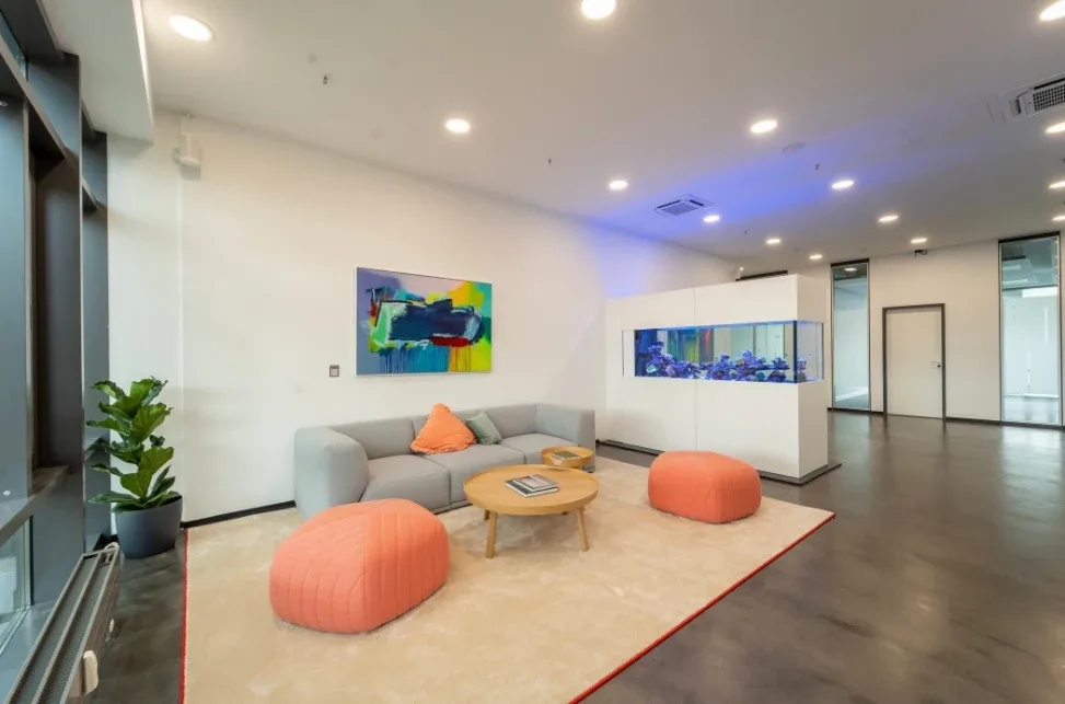 Helle Lounge mit Sofa, Sitzkissen und einem Aquarium als Raumteiler.